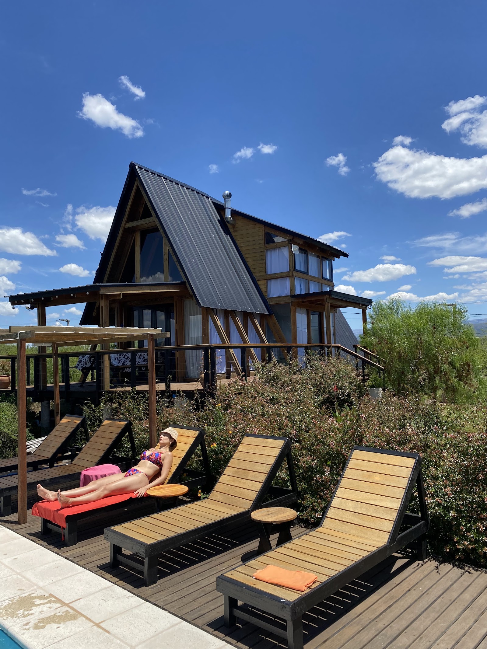Cabaña A-frame de madera de TORII con piscina y reposeras bajo el cielo despejado de las sierras
